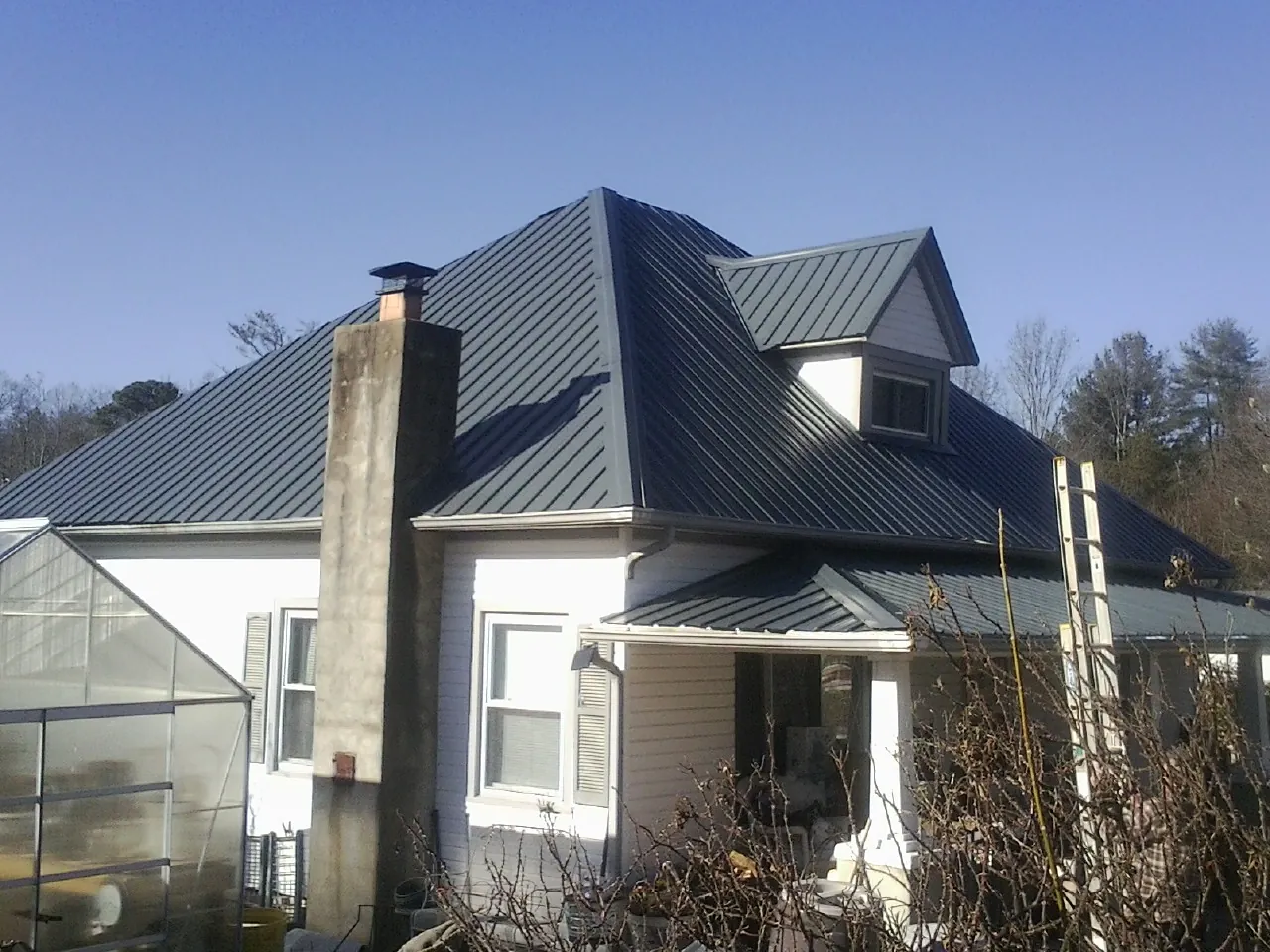 Dark blue standing seam metal roof on a white farmhouse with dormer — Slate & Tile Roof Repair by Roofing Brothers in Camp Dennison