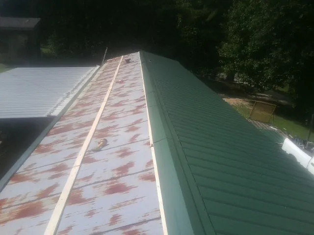 Old rusted panels beside newly installed green metal roofing — Wind Damage Roof Repair by Roofing Brothers in Camp Dennison