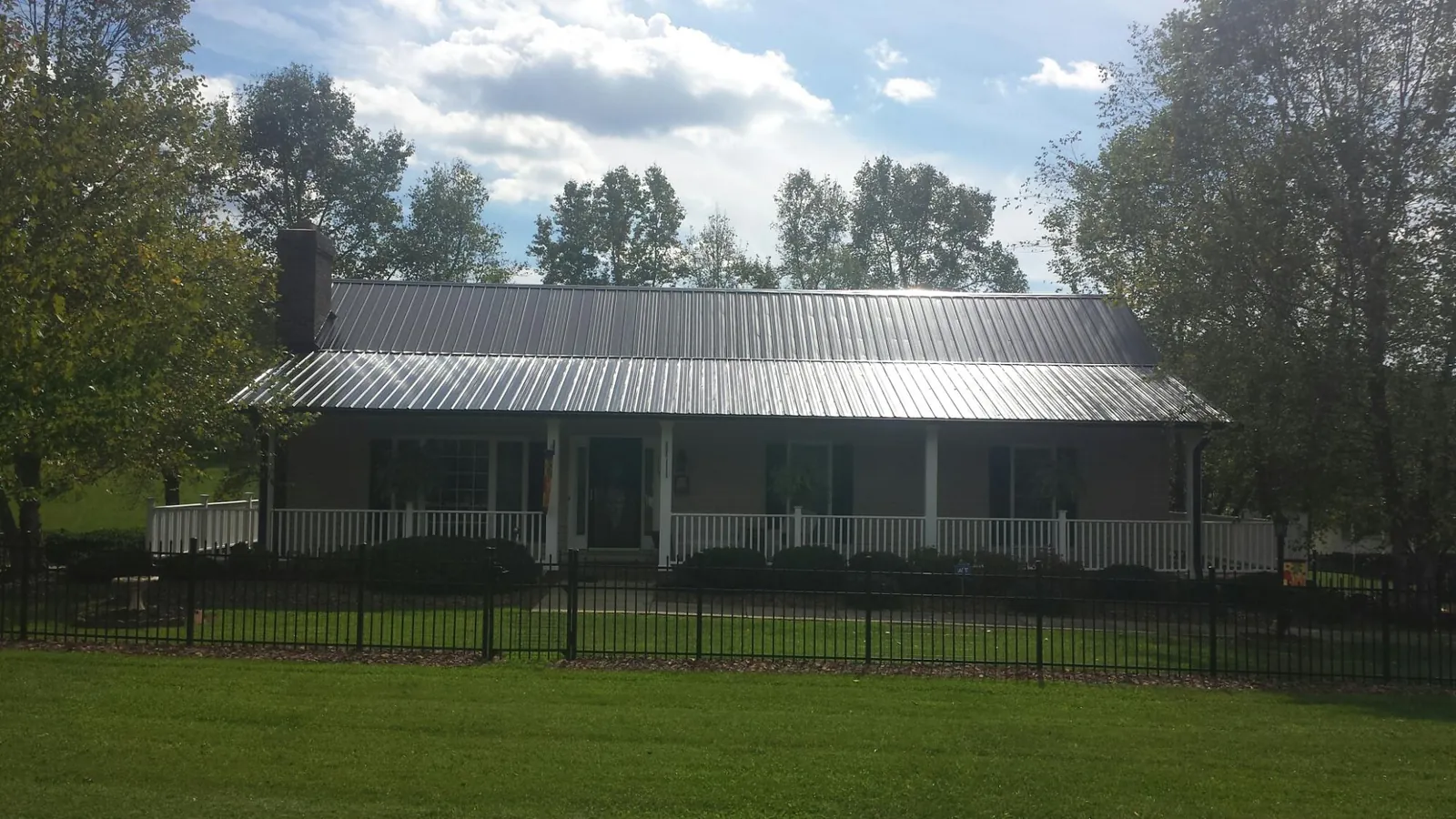 Gray metal roof on a brick ranch with a full width front porch — Gutter Guard Installation work by our crew in Camp Dennison