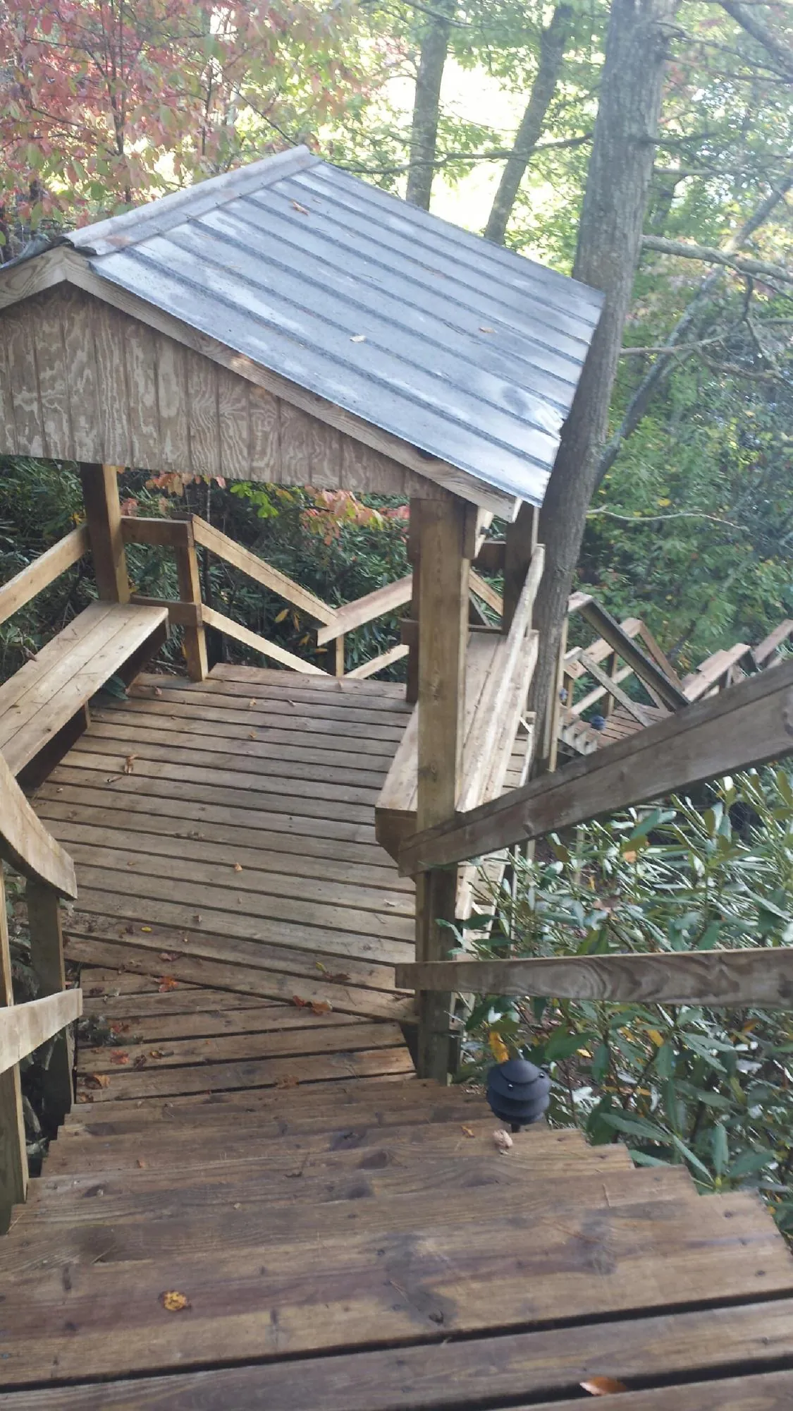 Metal roofed shelter over wooden steps on a wooded walkway — Skylight Repair & Installation work by our crew in Camp Dennison
