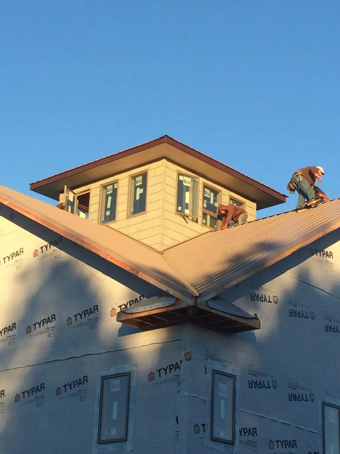 Roofers working around a rooftop cupola on a new metal roof at sunset — Roof Waterproofing in Camp Dennison by Roofing Brothers